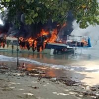 Touristen sehen zu wie ihr Schnellboot in Phang Nga in Flammen aufgeht