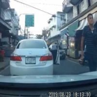 Wütender Autofahrer bedroht einen anderen Fahrer mit einer Waffe