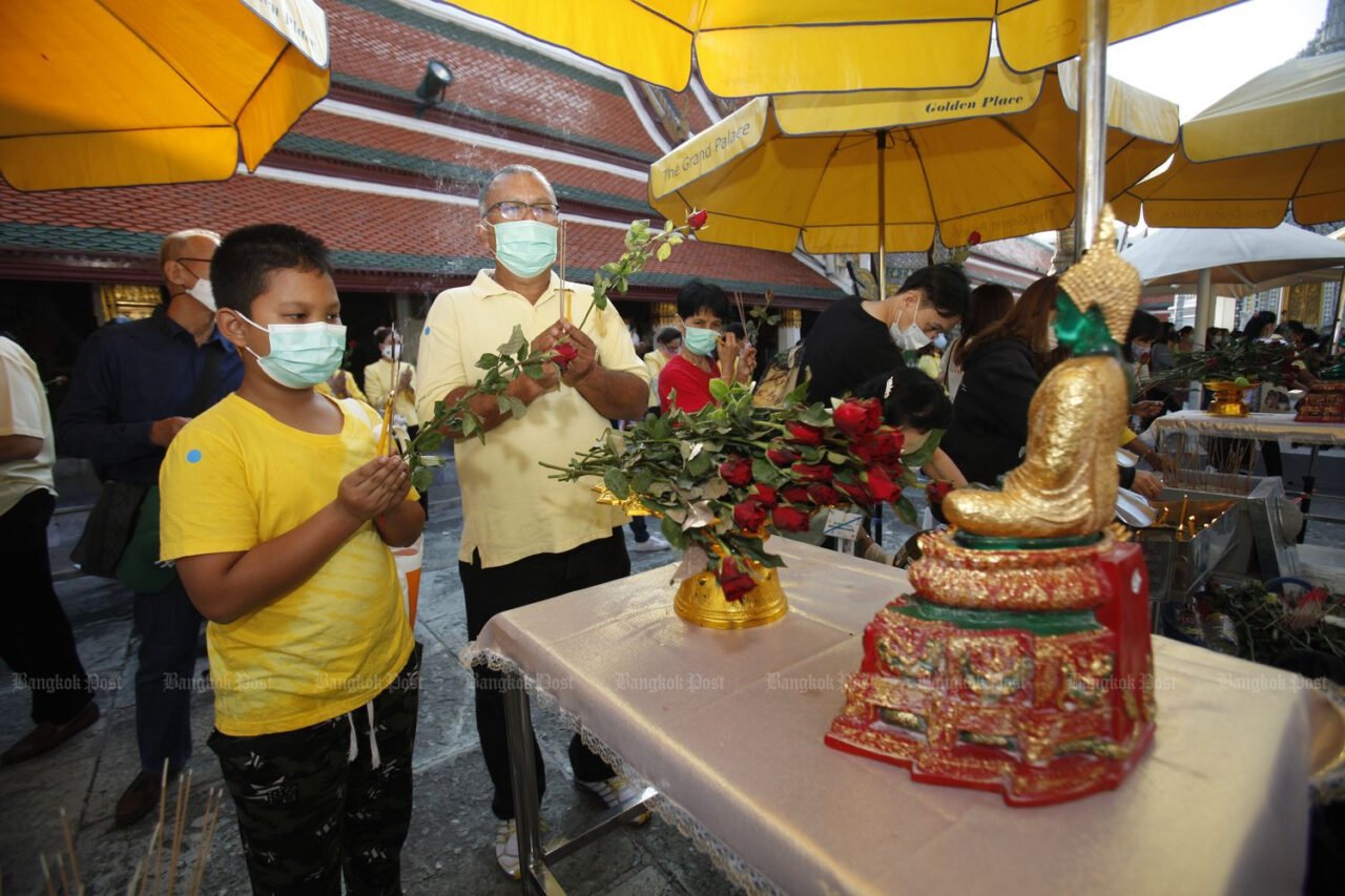 Ein Mann und ein Junge huldigen dem Smaragd-Buddha im Wat Phra Si Rattana Satsadaram (Wat Phra Kaeo) in Bangkok