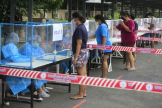 Die Menschen erhalten am Freitag Warteschlangentickets für Covid-19 Tests an der Chandrakasem Rajabhat University im Bezirk Chatuchak in Bangkok