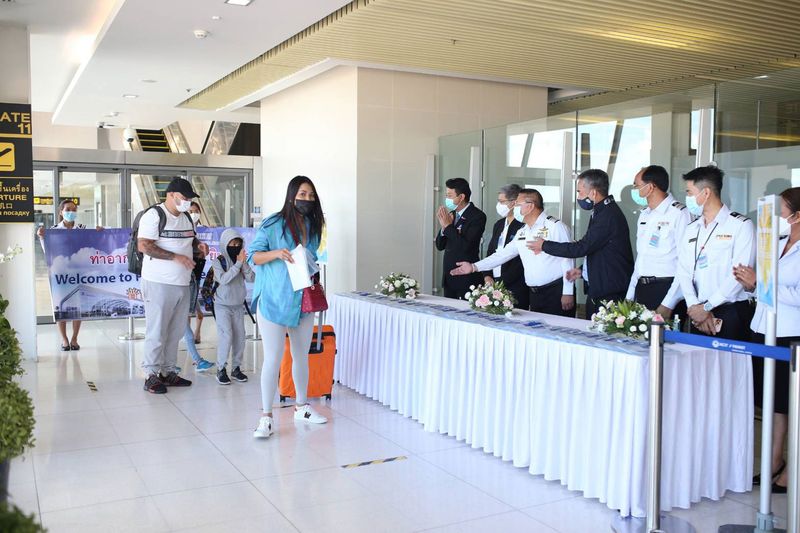 Die Passagiere werden am Flughafen Phuket begrüßt, da sie zu den ersten 23 Touristen gehören
