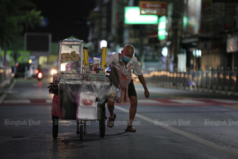 Ein Streetfood-Verkäufer kämpft am 24. Juli 2021 nachts damit, seinen Karren über eine fast menschenleere Straße in der Nähe des Hauptpiers von Nonthaburi zu schieben