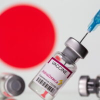 Auf diesem Illustrationsfoto vom 14. März 2021 sind Fläschchen mit der Aufschrift Astra Zeneca COVID-19 Coronavirus Vaccine und eine Spritze vor einer angezeigten japanischen Flagge zu sehen