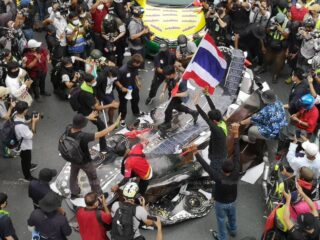 Demonstranten treten auf ein Modell eines Panzers, der von einem Taxi des Protestführers Nattawut Saikuar plattgedrückt wurde.
