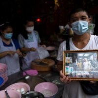 Adulwitch Tangsupmanee, 42, hält ein Bild seines Vaters Chanchai Tangsupmanee hoch, der im Juli im Alter von 73 Jahren an der Coronavirus Krankheit starb