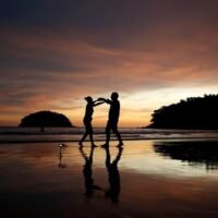 Die Anwohner Stavros aus Griechenland und Valina aus Russland tanzen an einem fast leeren Kata Strand, während Phuket wieder für ausländische Touristen geöffnet wird