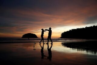 Die Anwohner Stavros aus Griechenland und Valina aus Russland tanzen an einem fast leeren Kata Strand, während Phuket wieder für ausländische Touristen geöffnet wird