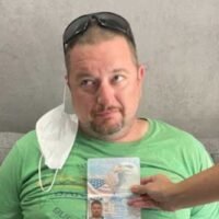 Ein Polizist hält Robert Gordons Reisepass an seinen Körper, um zu zeigen, dass das Bild mit dem Verdächtigen während seiner Festnahme in einem Hotel in Soi Nana am Samstag übereinstimmt