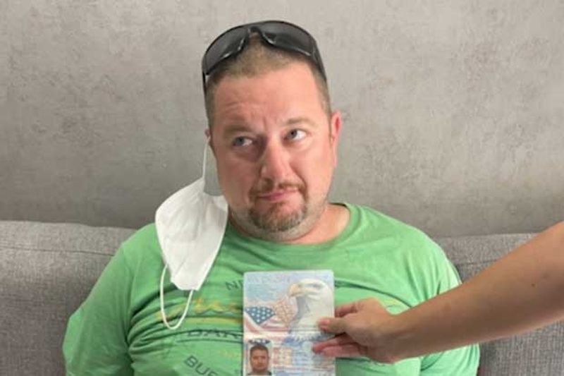 Ein Polizist hält Robert Gordons Reisepass an seinen Körper, um zu zeigen, dass das Bild mit dem Verdächtigen während seiner Festnahme in einem Hotel in Soi Nana am Samstag übereinstimmt