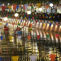 Touristen fahren mit dem Kajak entlang des Ong-Ang Kanals in Bangkok, der mit bunten Fahnen und Laternen geschmückt ist, um die Stimmung bei den Bewohnern aufzuhellen