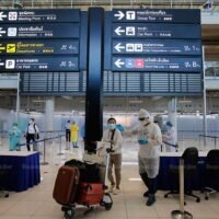 Touristen werden bei der Ankunft am internationalen Flughafen Suvarnabhumi von Gesundheitsbeamten begrüßt
