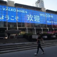 Zurück im Geschäft -Willkommen in Thailand wird in sieben Sprachen auf dem PanOramix-Bildschirm der CentralWorld in Bangkok angezeigt