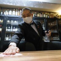 Der Besitzer einer Bar wischt einen Tisch mit Desinfektionsmittel ab, bevor er am 1. November dieses Jahres in der Stadt Naha in der Präfektur Okinawa im Süden Japans für die Nacht öffnet. Die lokalen Behörden hoben die Covid-19 Beschränkungen am selben Tag auf.