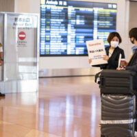Ein aus Übersee ankommender Passagier wird am Montag (8. November) von einem Quarantäne Agenten in der Ankunftshalle des Flughafens Haneda in Tokio empfangen