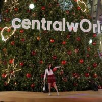 Eine Frau posiert für ein Foto vor dem höchsten künstlichen Weihnachtsbaum Südostasiens vor dem Einkaufszentrum CentralWorld. 'Shine Together' ist das Thema dieser Ausstellung