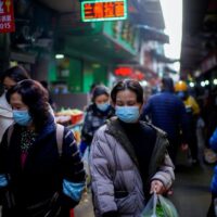 Menschen, die Gesichtsmasken tragen, gehen im Februar dieses Jahres über einen Straßenmarkt in Wuhan, China