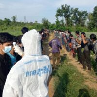Sicherheitskräfte messen die Temperatur eines Migranten aus Myanmar, der diesen Monat illegal in den Bezirk Sai Yok in Kanchanaburi eingereist ist