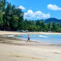 Touristen gehen am 1. November 2021 an einem Strand auf der thailändischen Insel Phuket, als Thailand die erste Gruppe von Touristen begrüßt,