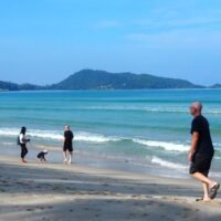 Touristen genießen einen Spaziergang am Strand von Patong in Phuket, da der Tourismus für die bevorstehende Hochsaison anzieht