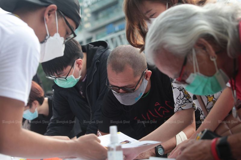 Während einer Kundgebung von Ratsadon Demonstranten an der Ratchaprasong Kreuzung in Bangkok am 31. Oktober füllen Menschen Formulare zur Unterstützung eines Gesetzes aus