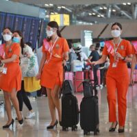 Das Kabinenpersonal der Regionalfluggesellschaft Thai Smile trägt beim Gang durch den Flughafen Suvarnabhumi Gesichtsmasken.