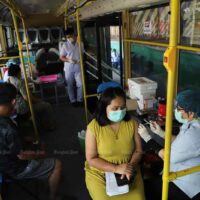 Die Menschen erhalten ihren Covid-19 Impfstoff am Dienstag in einem zu einer Impfstelle umgebauten Bus im Bezirk Klong Toey in Bangkok.
