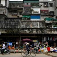 Dieses Aktenfoto vom 31. März 2021 zeigt eine Frau, die mit ihrem Fahrrad unter einem Wohnhaus in Hanoi an Geschäften vorbeifährt.