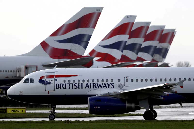 Ein Flugzeug von British Airways rollt an Heckflossen geparkter Flugzeuge vorbei zur Startbahn in der Nähe von Terminal 5 des Flughafens Heathrow in London, Großbritannien