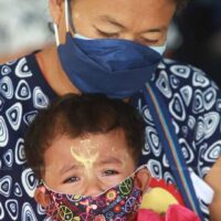 Eine Migrantin tröstet ihr weinendes Kind, während sie im Bang Phli Hospital in Samut Prakan auf einen Covid-19-Impfstoff wartet.