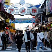 Fußgänger mit Schutzmasken machen sich am Mittwoch im Einkaufsviertel Ameyoko in Tokio auf den Weg.