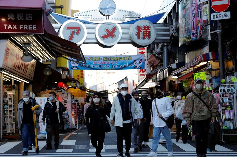 Fußgänger mit Schutzmasken machen sich am Mittwoch im Einkaufsviertel Ameyoko in Tokio auf den Weg.