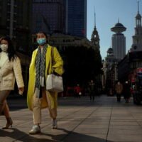 Menschen mit Schutzmasken gehen am Mittwoch in Shanghai auf einer Straße.