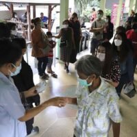 Die Menschen stehen am Donnerstag an, um Warteschlangenkarten für Covid-19 Impfungen im Pathumthani Krankenhaus im Bezirk Muang von Pathum Thani abzuholen