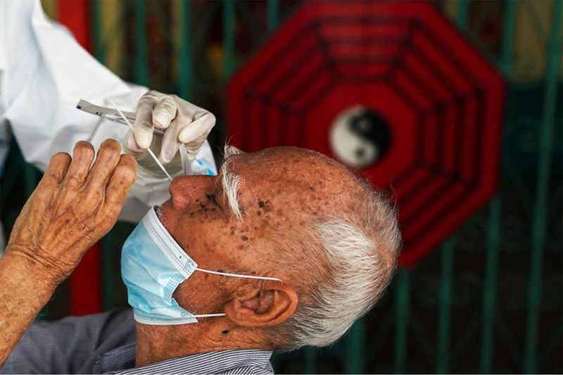 Ein Gesundheitspersonal der Zendai-Organisation entnimmt einem Mann am Mittwoch in Bangkok einen Nasenabstrich für einen Antigen-Schnelltest.