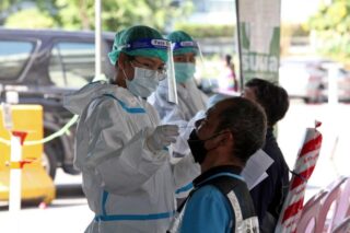 Ein Gesundheitspersonal wischt einen Mann auf Covid-19 in einem Drive-Through Testzentrum am südlichen Busbahnhof an der Boromratchonnanee Road im Bezirk Taling Chan ab