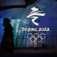 Ein Mann geht am Samstag in Peking an einem beleuchteten Schild für die Olympischen Winterspiele vorbei.