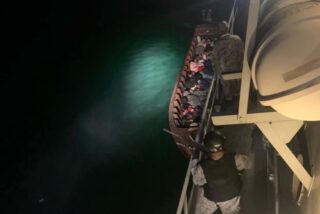 Ein großes Marineschiff nimmt das Langheckboot und seine illegalen Migranten aus Myanmar fest. (Foto - Drittes Marinegebiet)