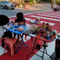 Kunden essen an einem Essensstand mit Tischen auf einem Fußgängerüberweg in Ubon Ratchathani.