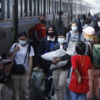 Menschen steigen am Sonntag nach ihrer Pause in den Provinzen während der Neujahrsfeiertage am Bahnhof Hua Lamphong aus einem Zug aus.