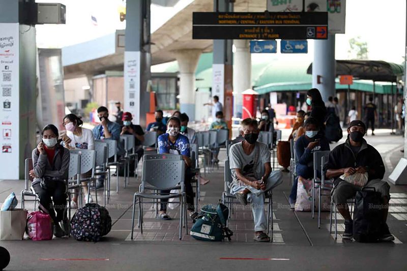 Reisende tragen Gesichtsmasken, um sich vor Covid-19 zu schützen, während sie am Mittwoch am Bangkok Bus Terminal auf ihre Busse warten