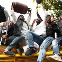 Aktivisten des Indischen Jugendkongresses (IYC) sitzen auf Polizeibarrikaden, während sie am 14. Dezember 2021 bei einem Protest gegen die Benzinpreiserhöhung in Neu-Delhi Parolen rufen