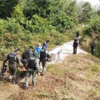 Beamte der Sprengstoffräumung tragen die beiden verletzten Mitglieder ihres Trupps am Freitagmorgen vom Ort der Explosion im Chana-Distrikt, Songkhla,