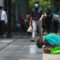 Ein Mann bittet am 20. April 2021 Fußgänger auf der Silom Road um Geld, da die Covid-19-Pandemie viele Menschen arbeitslos machte.