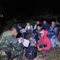 Ein Soldat sucht Details von illegalen Migranten, nachdem sie in Kanchanaburi bei der illegalen Einreise in das Land erwischt wurden