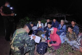 Ein Soldat sucht Details von illegalen Migranten, nachdem sie in Kanchanaburi bei der illegalen Einreise in das Land erwischt wurden