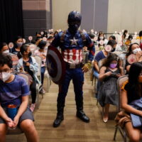 Ein als Captain America verkleideter Mann steht am 7. Februar 2022 in Taguig City, Metro Manila, inmitten von Kindern und Eltern