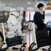 Menschen, einige in voller Schutzausrüstung, stehen am Montag zum Check-in für ihre Flüge am Flughafen Suvarnabhumi an.