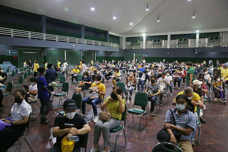 Menschen füllen ein Auditorium an der Kasetsart Universität, während sie auf die dritte oder vierte Impfung mit dem Pfizer Impfstoff warten