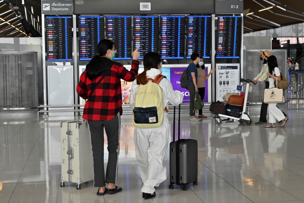 Passagiere, die Gesichtsmasken und einen Schutzanzug als vorbeugende Maßnahme gegen das COVID-19-Coronavirus tragen, kommen am Abflugterminal des Flughafens Suvarnabhumi in Bangkok an.