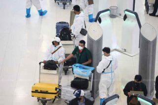 Reisende schützen sich am Mittwoch am Flughafen Suvarnahumi in Samut Prakan vor einer Infektion, als das Land 23.557 neue Covid-19 Fälle und 38 weitere Todesfälle verzeichnete.